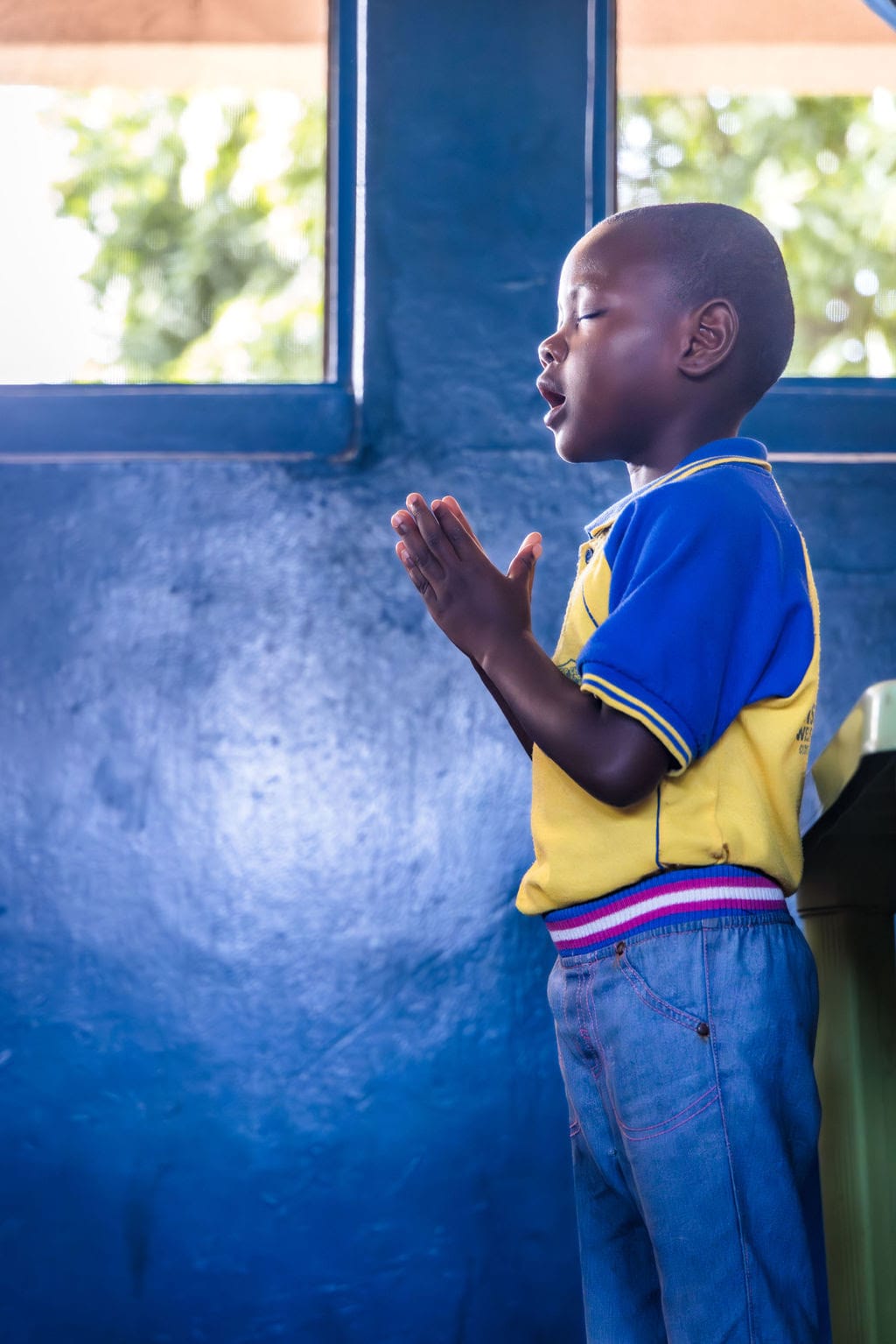 Child praying in room with blue walls - The Prayer Chain of Connection
